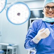 Surgeon standing in an operating room with her gloved hands in front of her, smiling, discussing Urinary Control after Prostate Surgery.