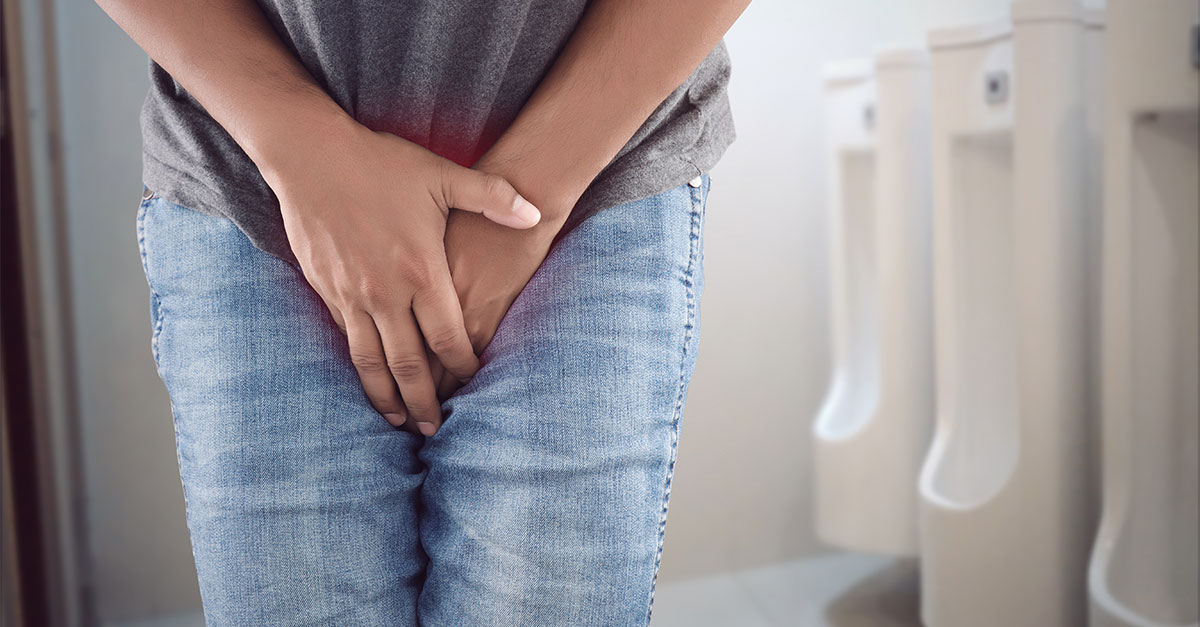 Male holding bladder near urinals.